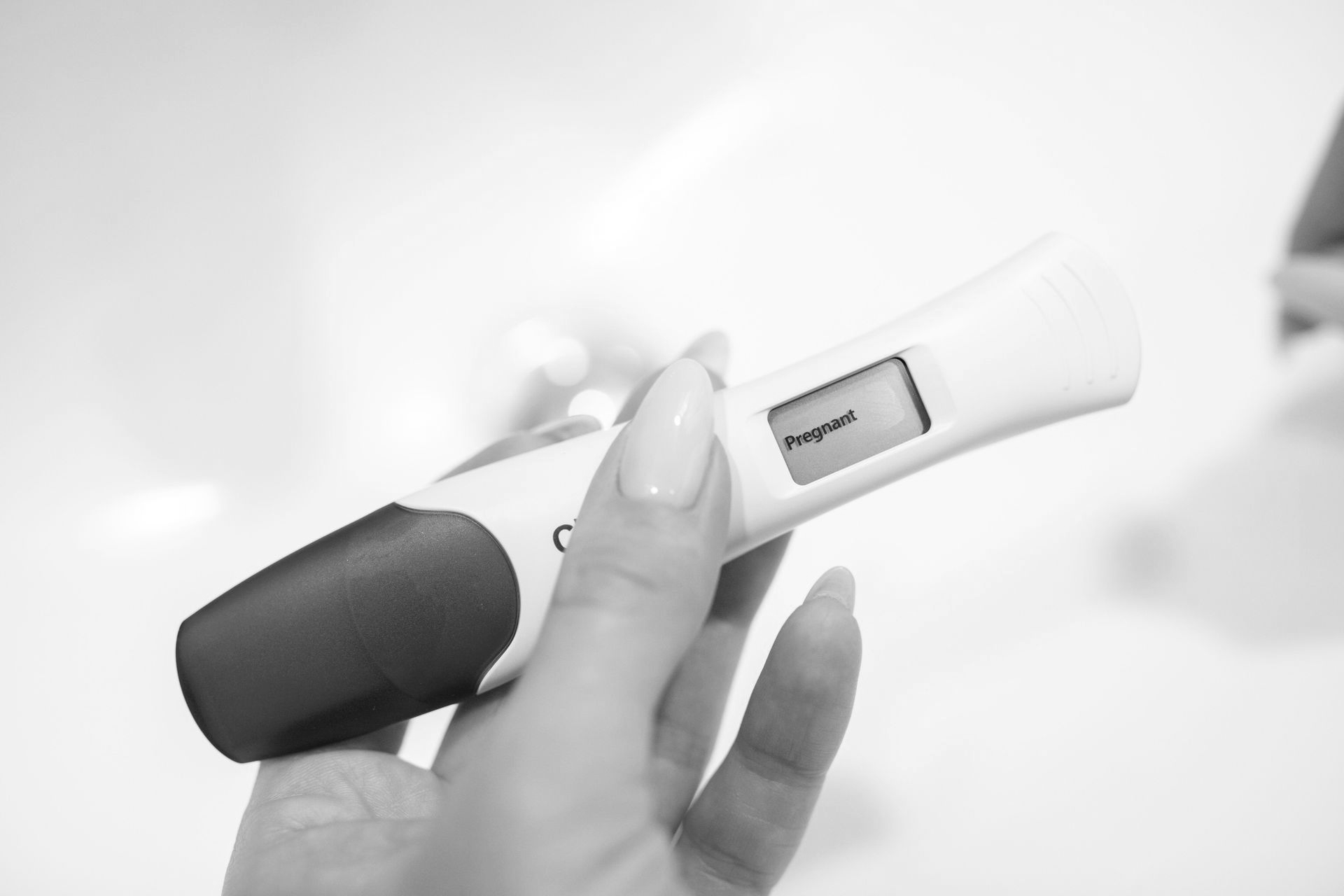 Hand holding a digital pregnancy test with a positive result display