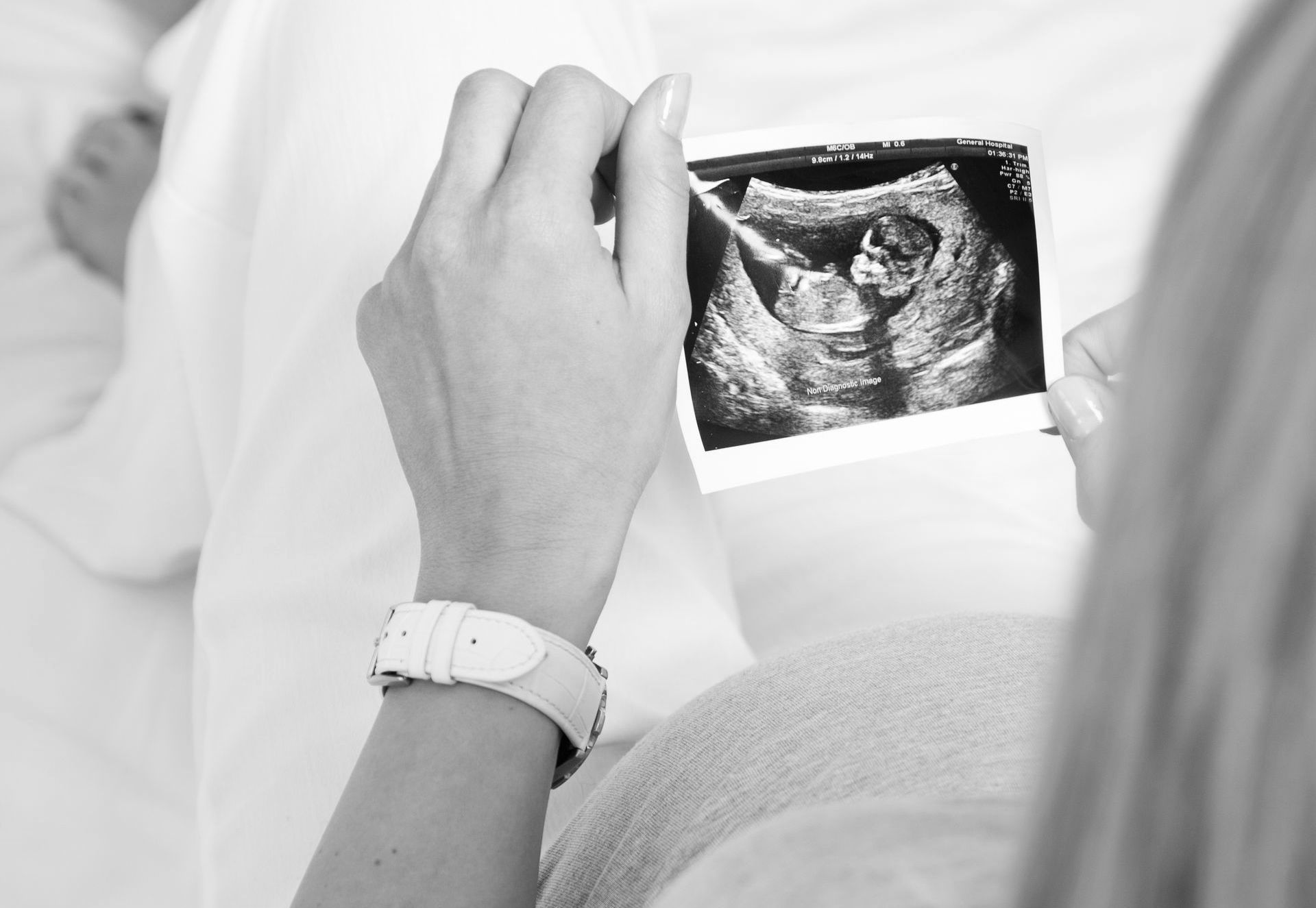 Pregnant woman holding and looking at an ultrasound image during a prenatal or pre-abortion screening.
