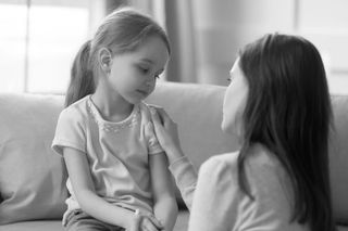 A woman counseling her toddler daughter.