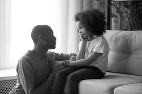 An African-American man counseling his young daughter.