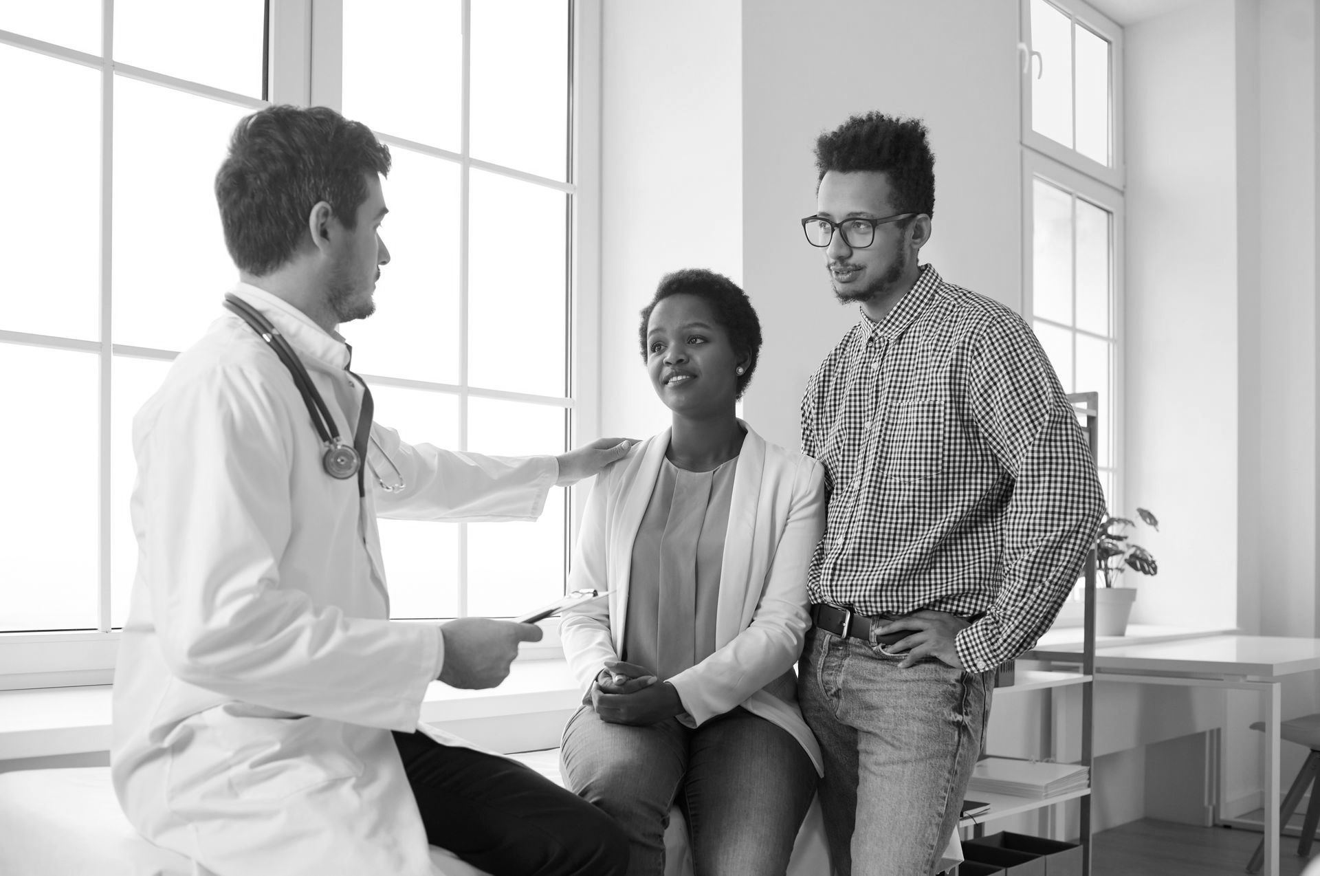 Doctor talking with a couple in a bright office, offering guidance and reassurance during consultation.