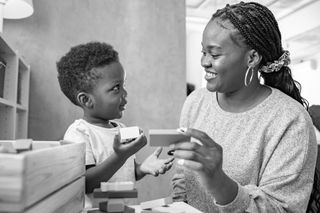 An African-American woman smiling and looking at her toddler son.