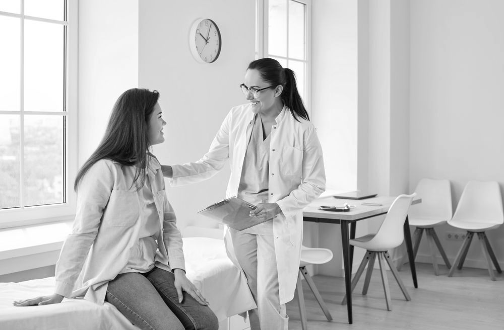A doctor is talking to a patient who is sitting on a bed.