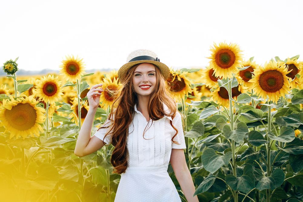 A smiling woman in a sunflower field.