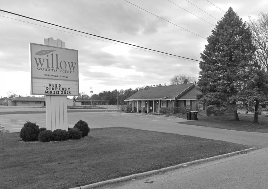Exterior view of Willow Women’s Center building with parking lot and sign displaying contact details.
