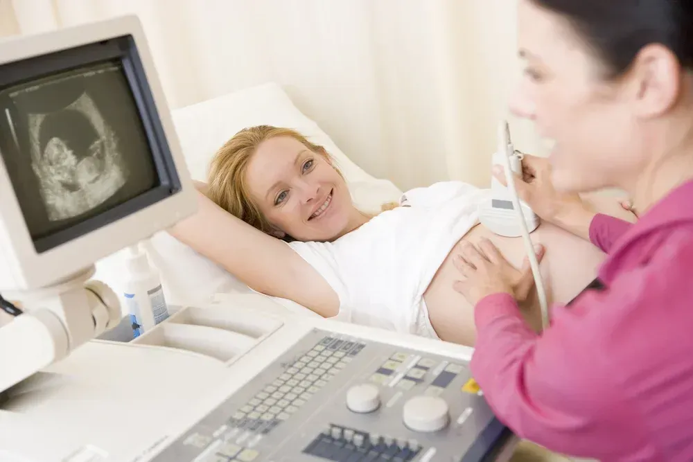 A pregnant woman is getting an ultrasound from a doctor.