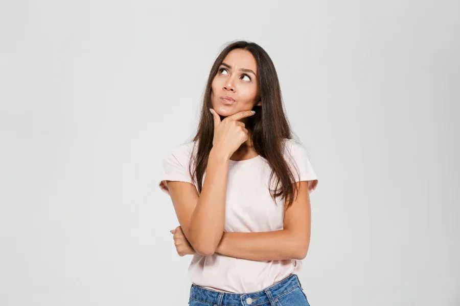 A woman is holding her hand to her chin and looking up.
