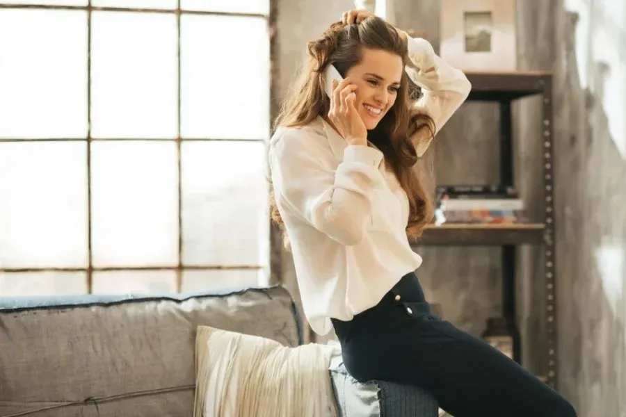 A woman is sitting on a couch talking on a cell phone.