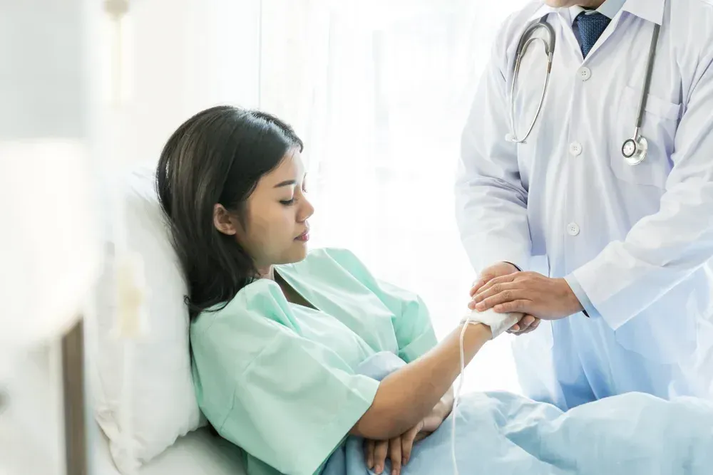 A woman is laying in a hospital bed talking to a doctor.