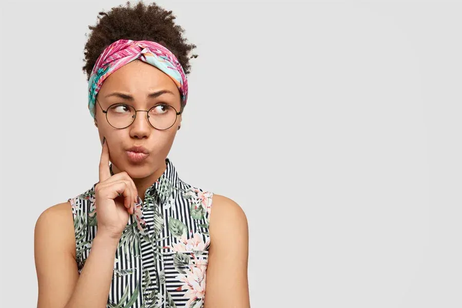 A woman wearing glasses and a headband thinking about something.