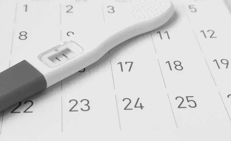 A pregnancy test is sitting on top of a calendar