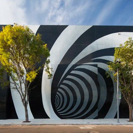 A black and white optical illusion is painted on the side of a building