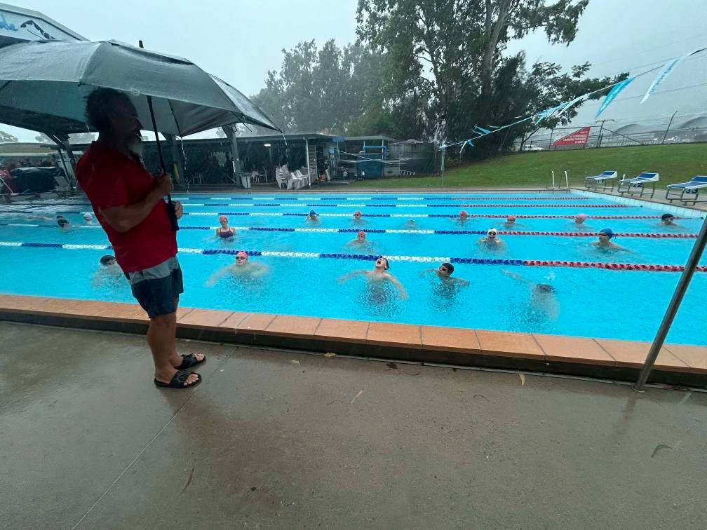 A Swim Instructor Overseeing a Group Swimming in an Outdoor Pool — Cannonvale Swim Centre In Cannonvale, QLD