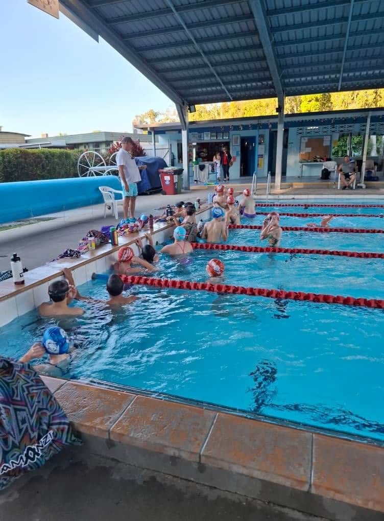 A Group of Swimmers Gather at the Edge of an Outdoor Pool — Cannonvale Swim Centre In Cannonvale, QLD