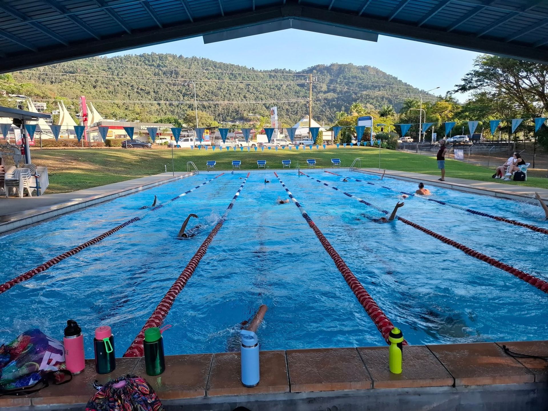 People Swimming In A Blue Outdoor Pool With Lane Markers — Cannonvale Swim Centre In Cannonvale, QLD