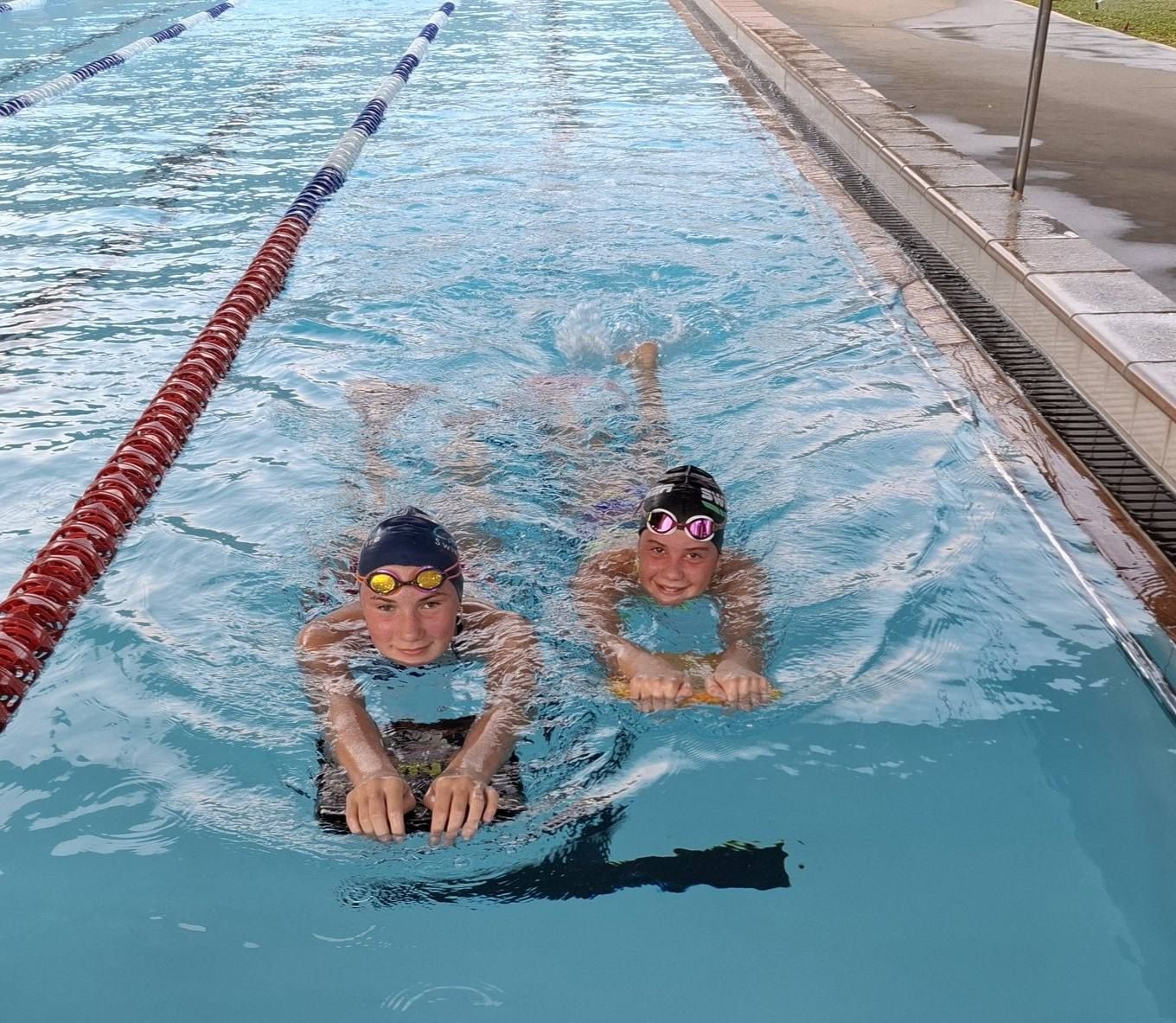 Two People In A Swimming Pool, Holding Kickboards — Cannonvale Swim Centre In Cannonvale, QLD