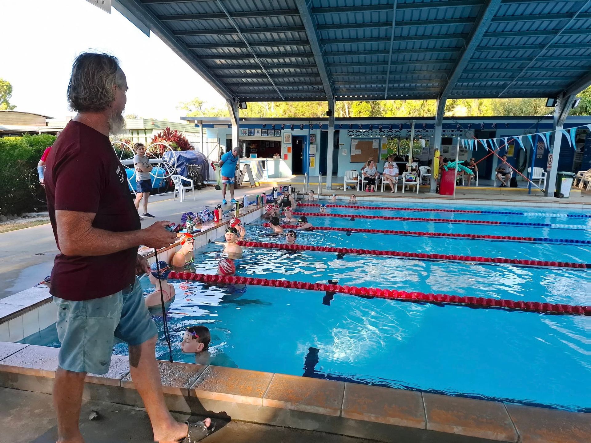 Man Observing A Swimming Race At A Pool Under A Covered Area — Cannonvale Swim Centre In Cannonvale, QLD