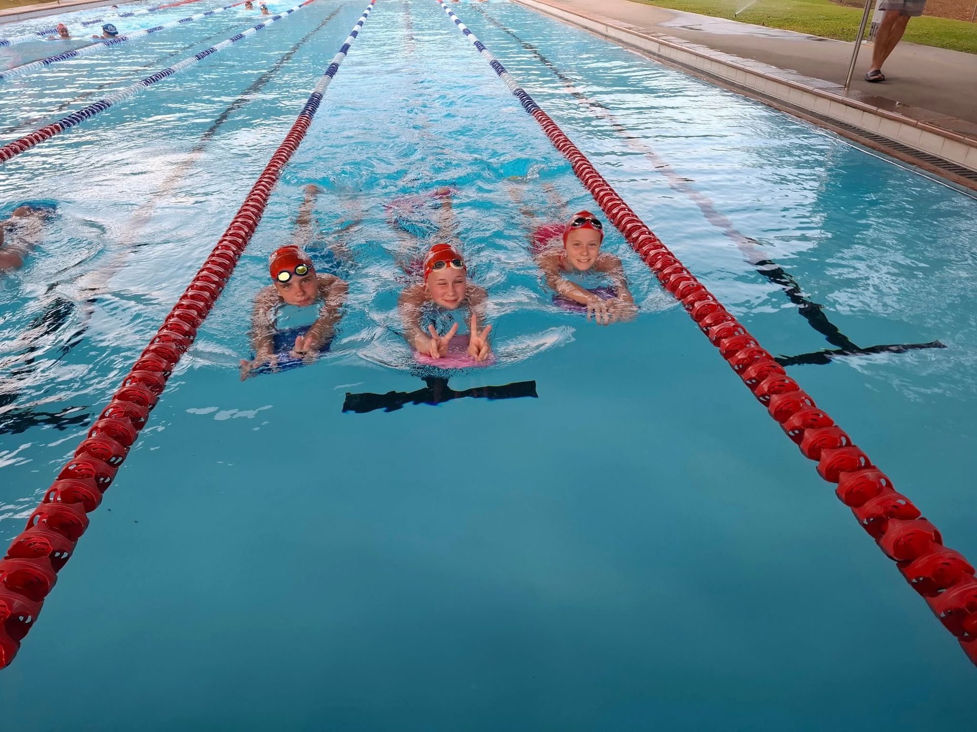 Three Swimmers Racing in a Lane of a Blue Outdoor Pool — Cannonvale Swim Centre In Cannonvale, QLD