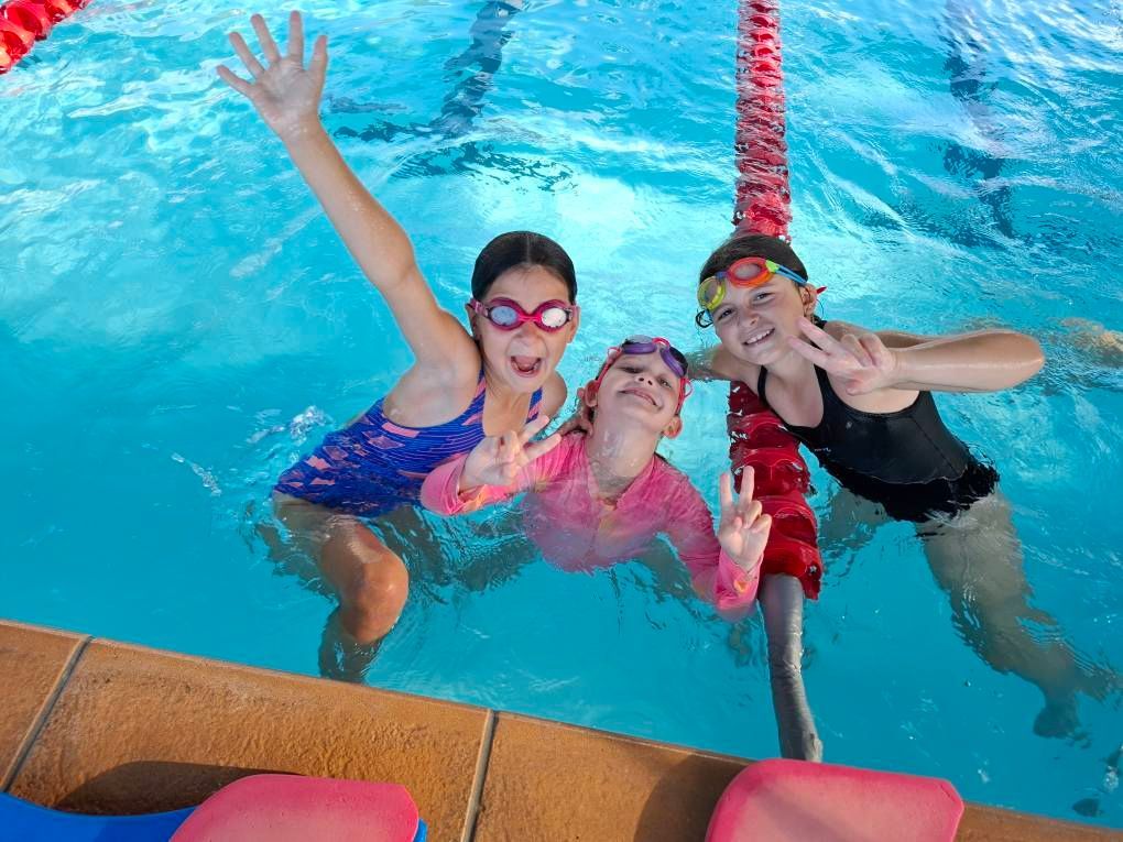 Three Children In A Swimming Pool, Smiling And Waving — Cannonvale Swim Centre In Cannonvale, QLD