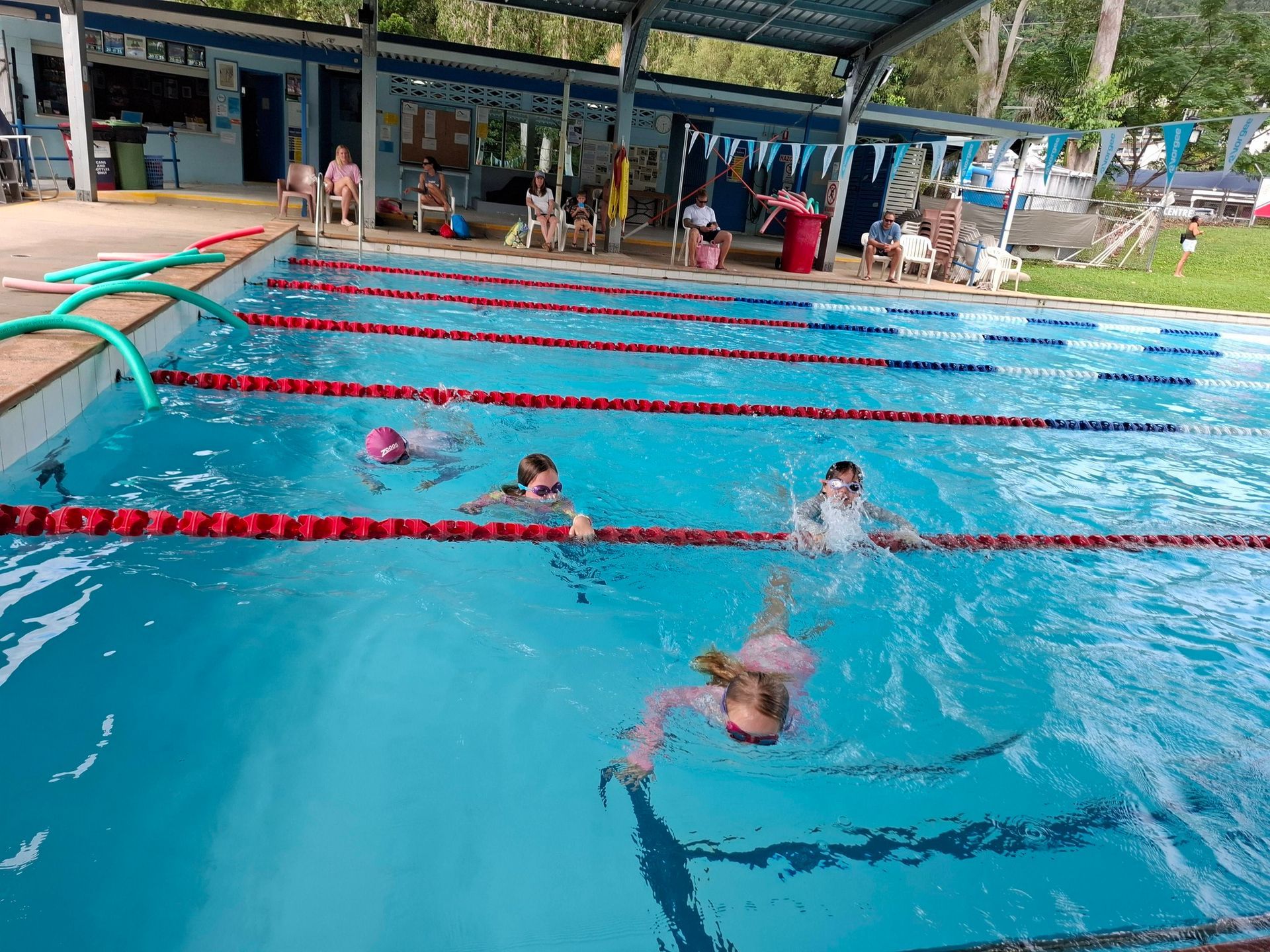 Children Swimming in a Blue Outdoor Pool With Red Lane Lines — Cannonvale Swim Centre In Cannonvale, QLD