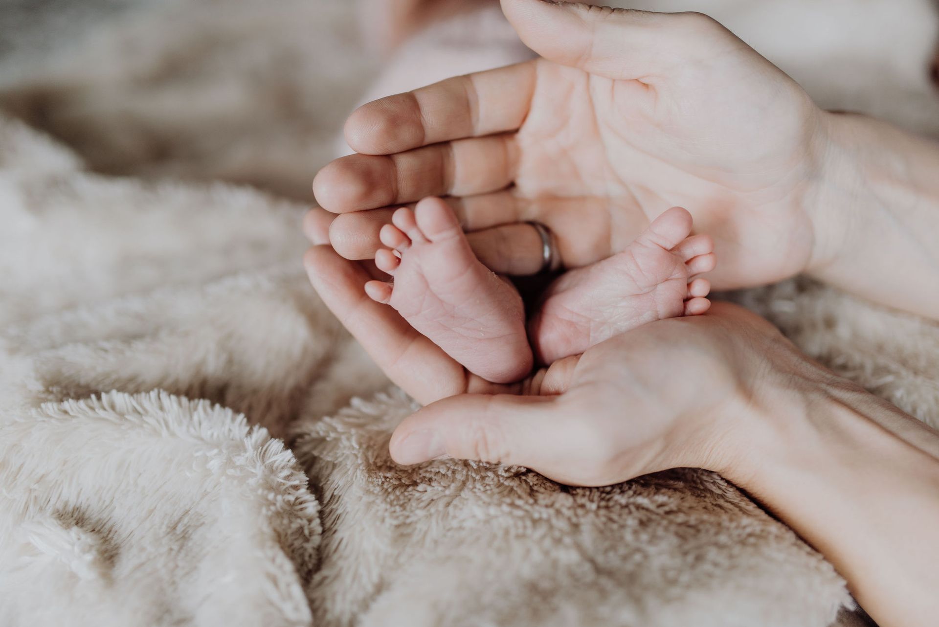 A postpartum mother is holding her newborn baby in her arms.