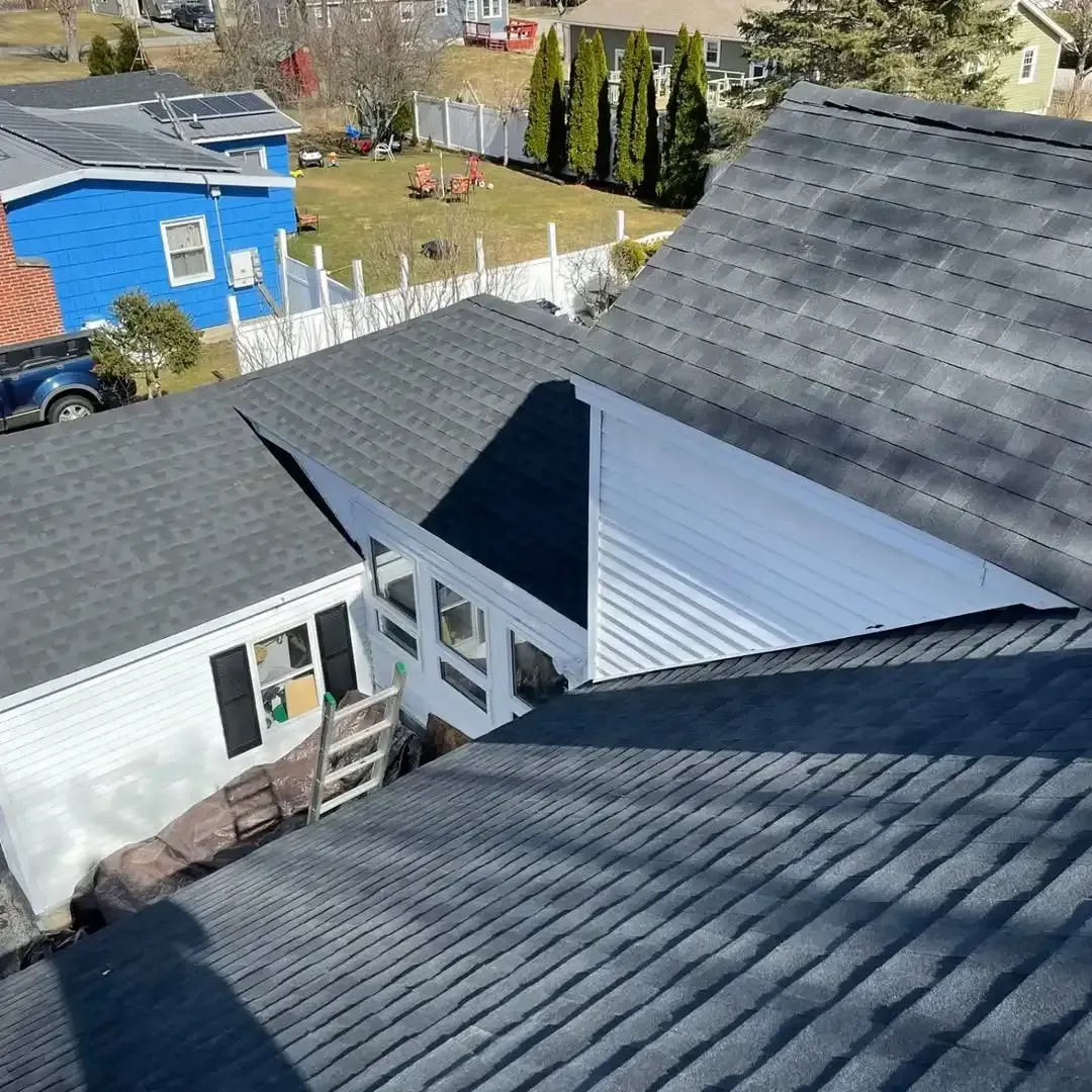 An aerial view of a roof of a house with a blue house in the background.