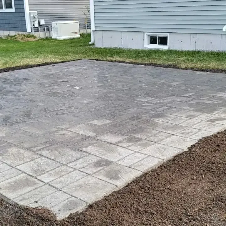 A brick patio is being built in front of a house.