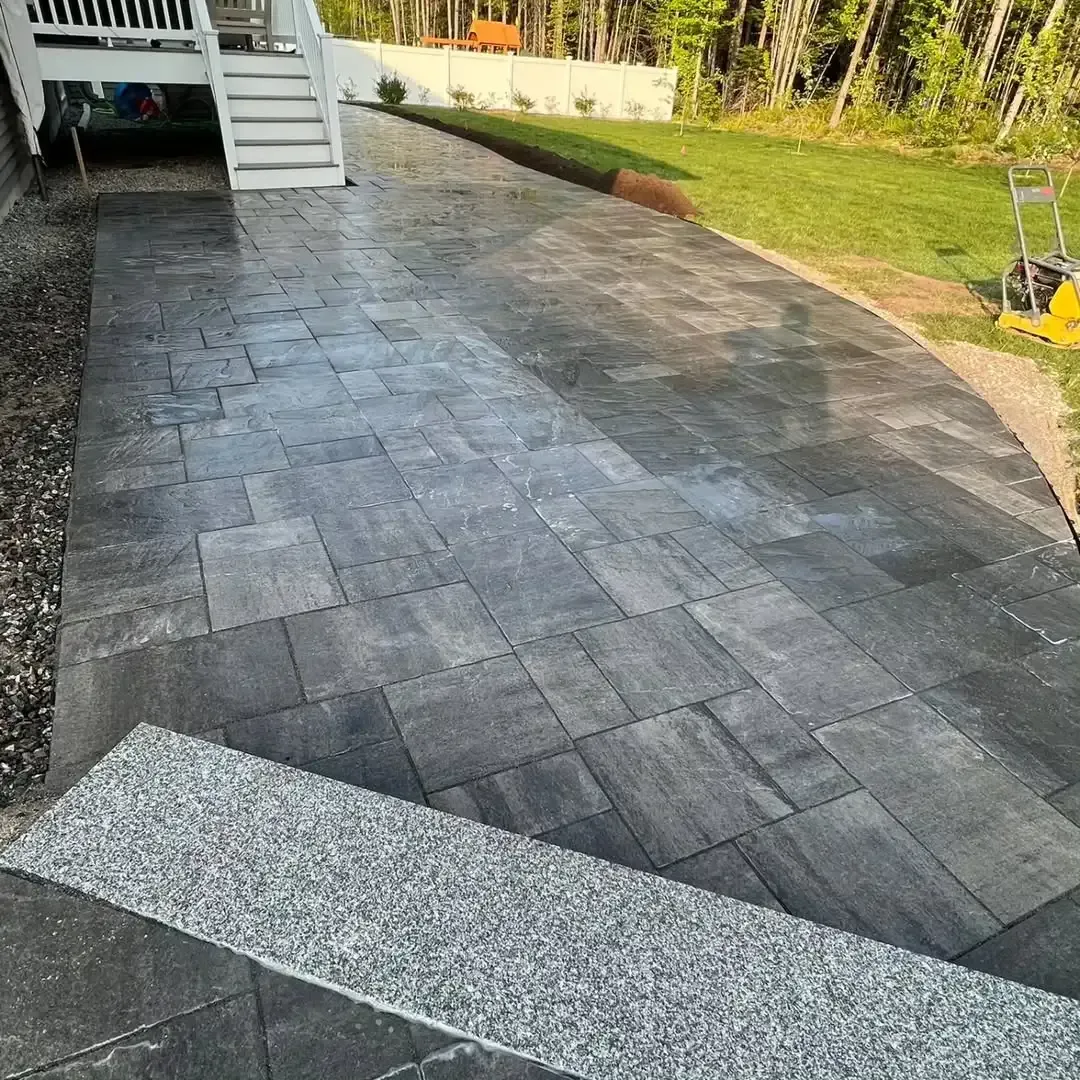 A brick walkway leading to a house with stairs.
