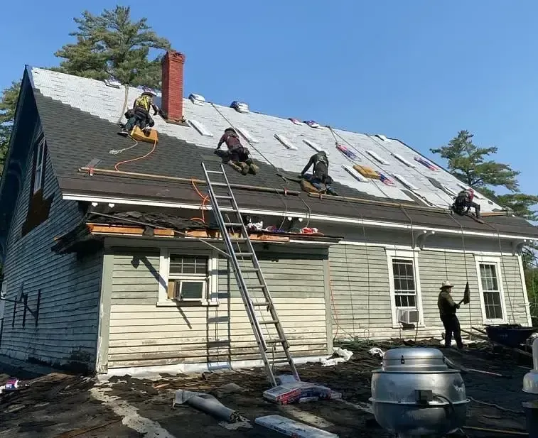 A group of people are working on the roof of a house.