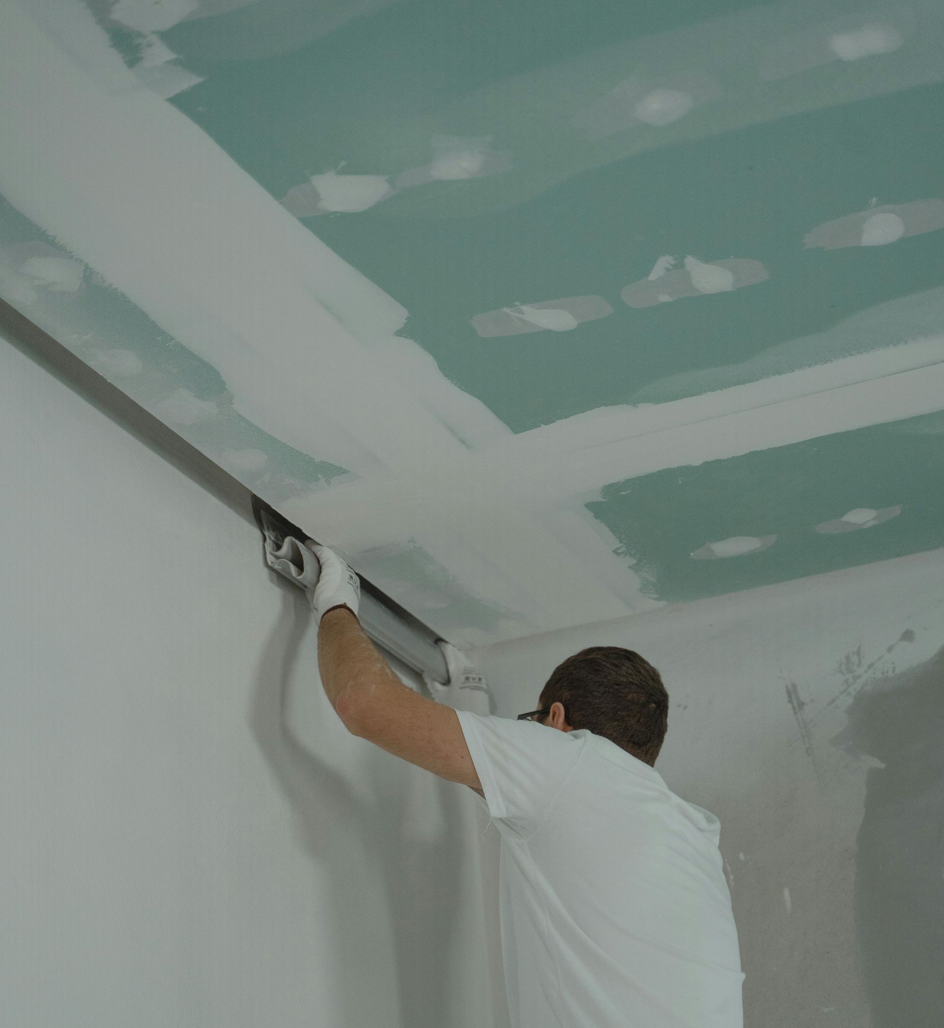 A man in a white shirt is working on a ceiling
