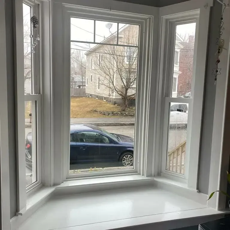 A car is parked in front of a large window in a living room.
