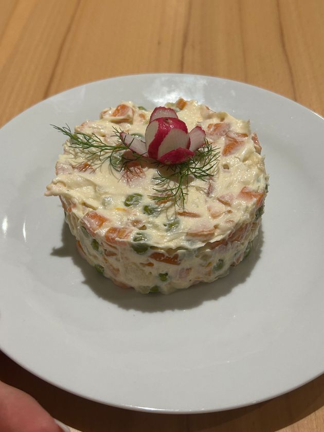 Tartare di tonno crudo su un piatto bianco, guarnita con fette d'arancia e verde.