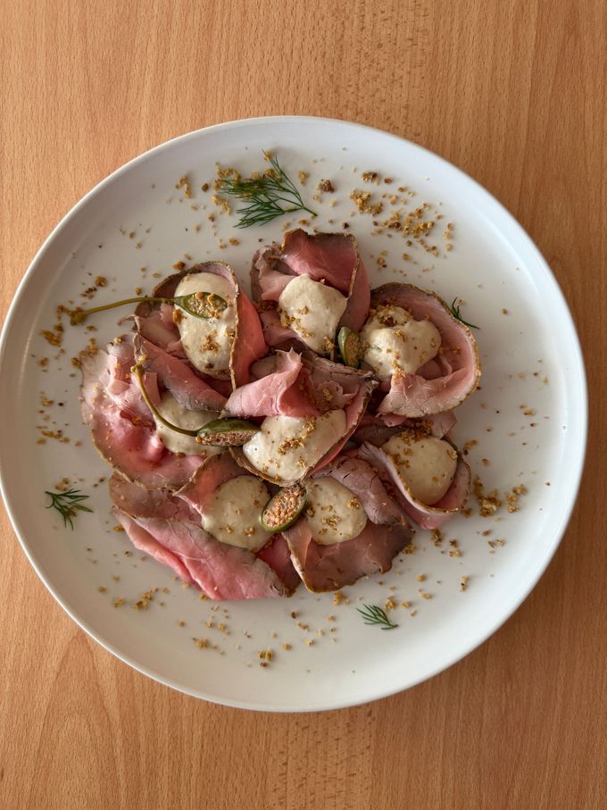 Misto di verdure con peperoni rossi, arancioni e verdi, su un piatto bianco decorato con pesci azzurri, guarnito con menta e pinoli.