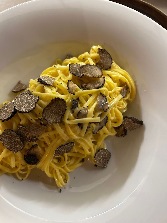 Misto di verdure con peperoni rossi, arancioni e verdi, su un piatto bianco decorato con pesci azzurri, guarnito con menta e pinoli.