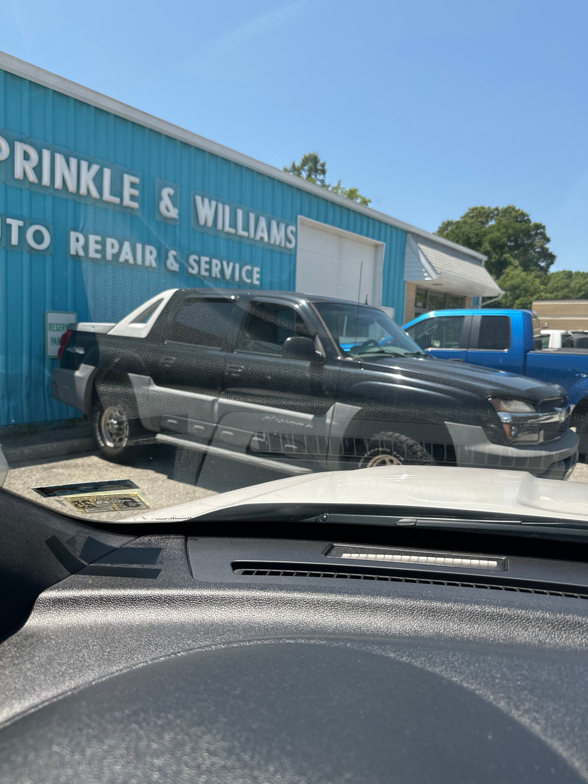 A black and silver Chevrolet Avalanche parked in front of a blue Sprinkle & Williams auto repair shop. | Sprinkle and Williams II, Inc.