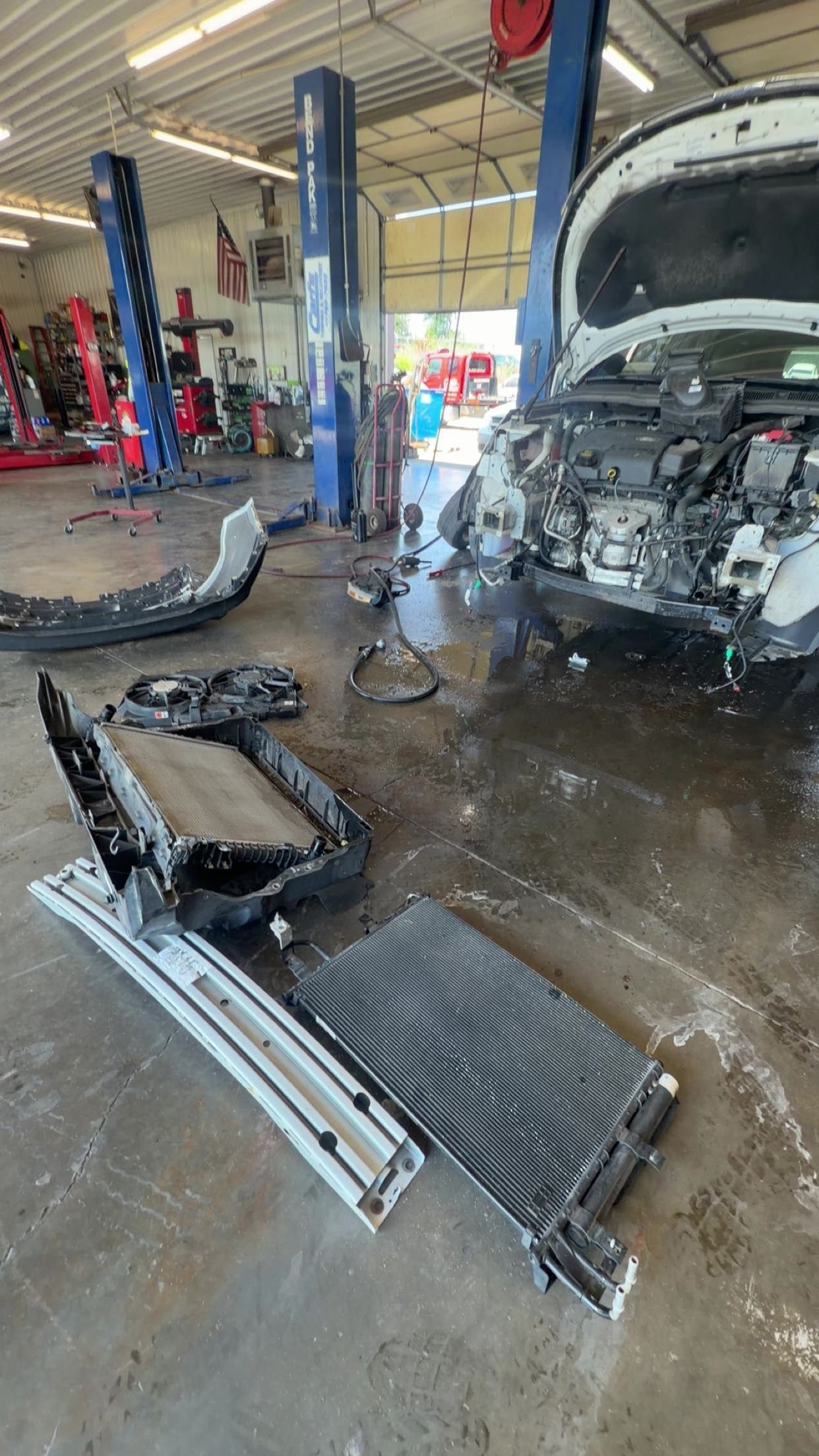 Auto repair shop with a vehicle in a service bay and removed car parts on the floor
