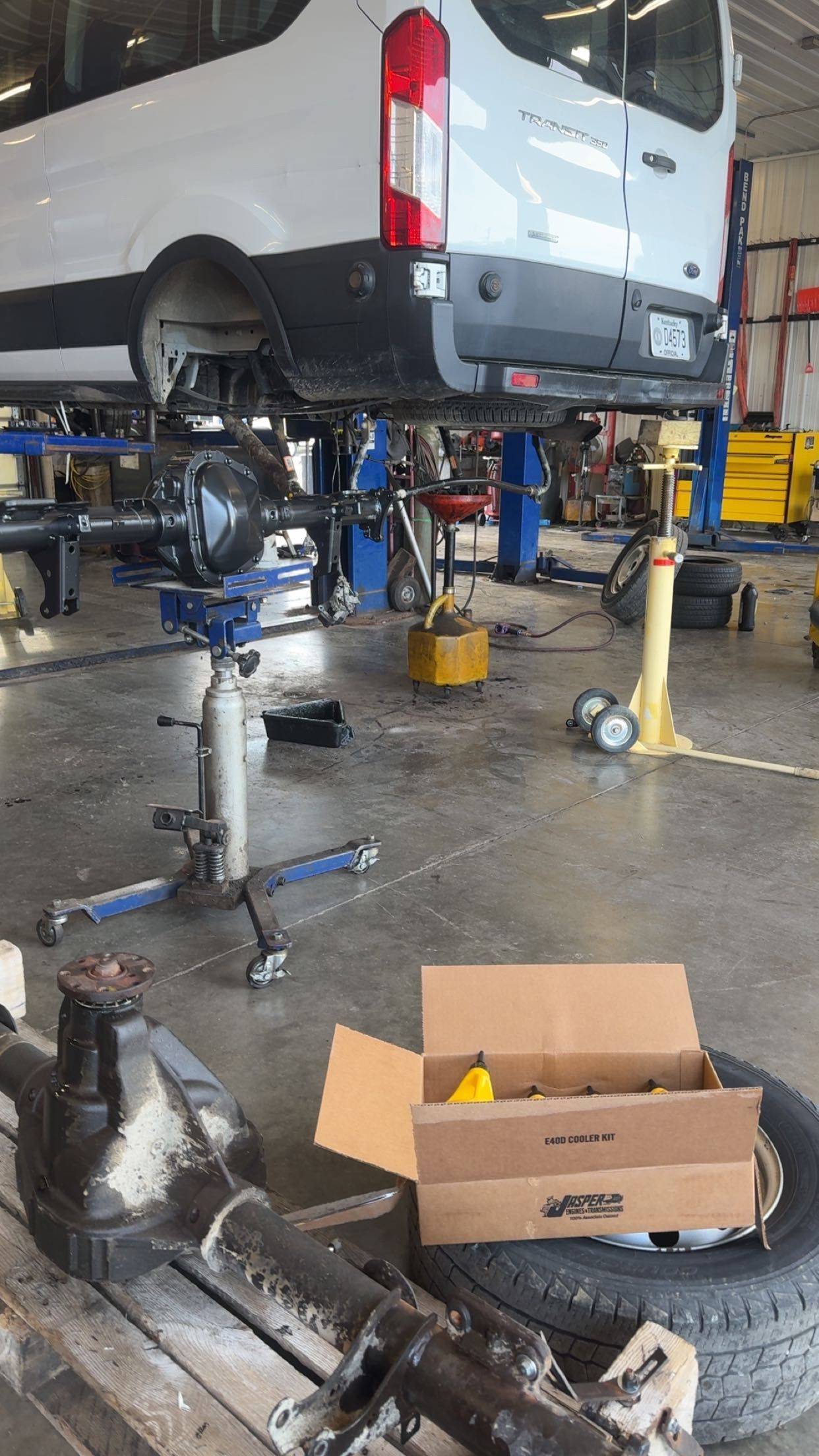 Pickup truck lifted in auto shop, with tools, parts, and tires on the floor
