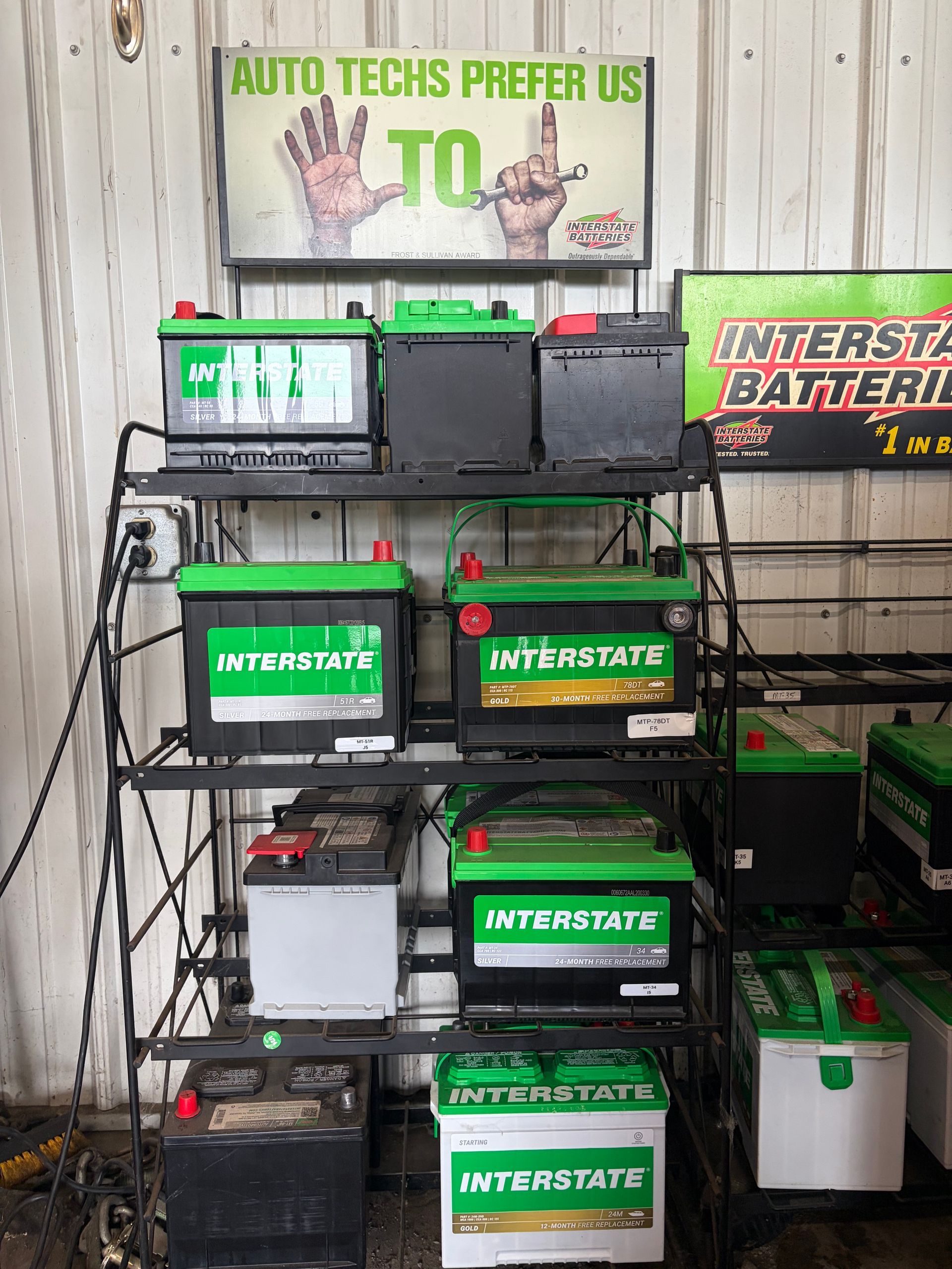 Battery display rack with Interstate Batteries signs and multiple green-and-black car batteries in a shop display