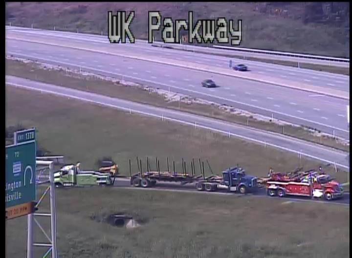 Tow truck and emergency vehicles on a highway shoulder near an overturned car on UK Parkway
