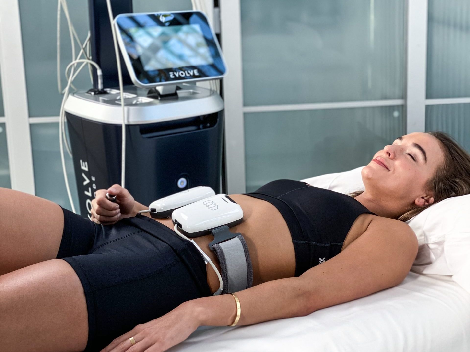 Woman receiving body contouring treatment with the EvolveX device in a medical office.