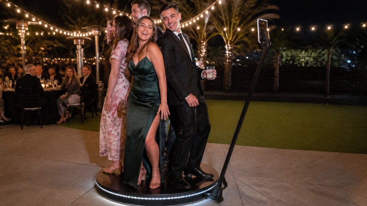 Wedding guests laughing on a 360 photo booth during an evening reception to help you understand 360 photo booth rental