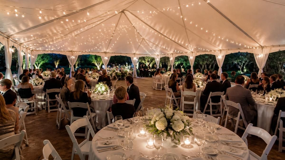 Elegant evening wedding tent rental featuring formal table settings and ambient string lighting for guests