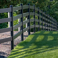 Black rail fence along a grassy path with sunlight and trees in the background