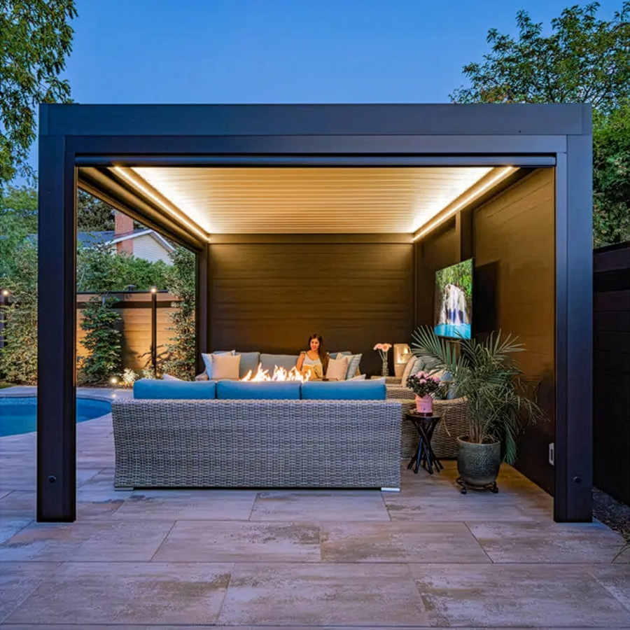Modern covered patio lounge with wicker sofa, warm lighting, potted plants, and blue evening sky
