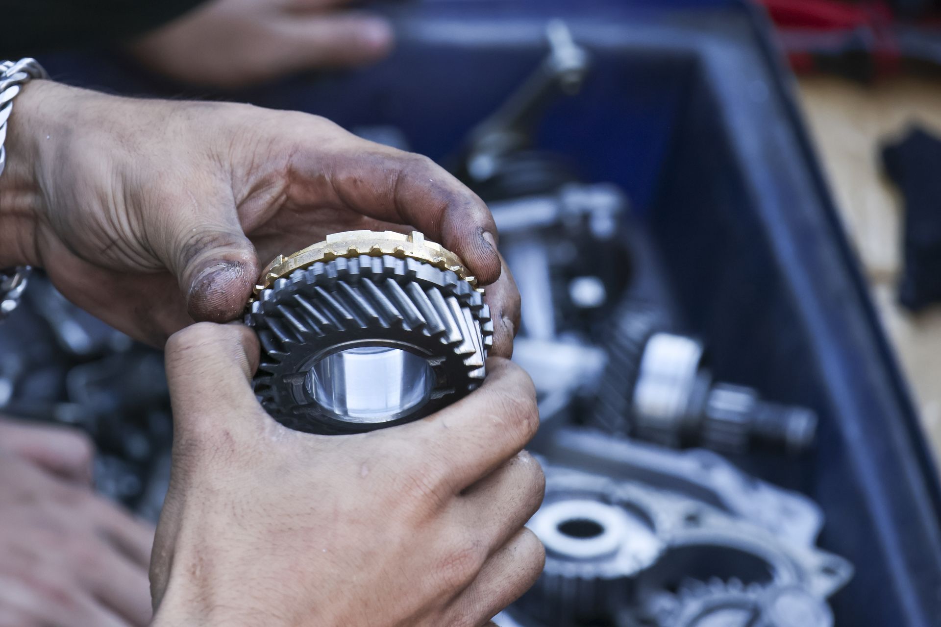 Close-up of a mechanic's hand holding a car's gear during transmission repair service in a workshop.