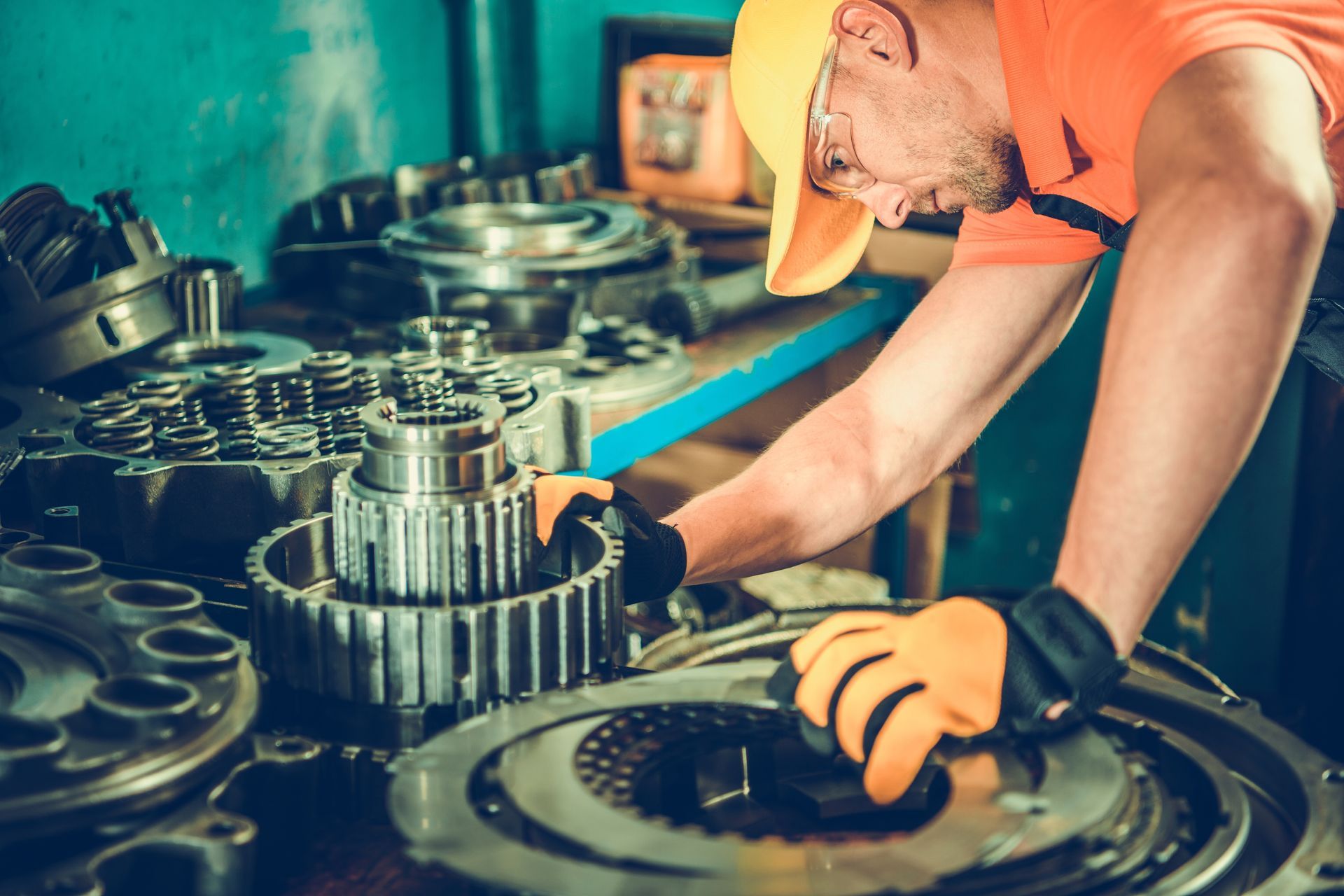 A man operates a machine in a factory, focused on his task amidst transmissions and gearboxes.