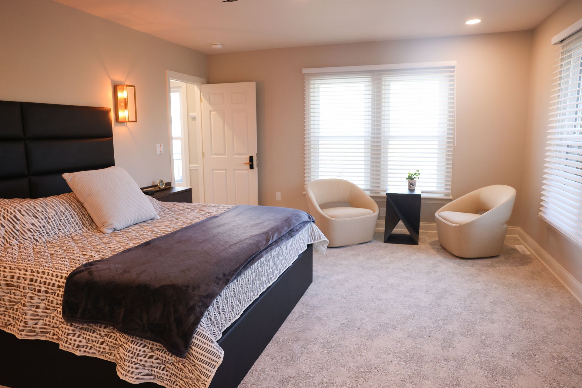A bedroom with a king size bed , dresser , chair and rug.