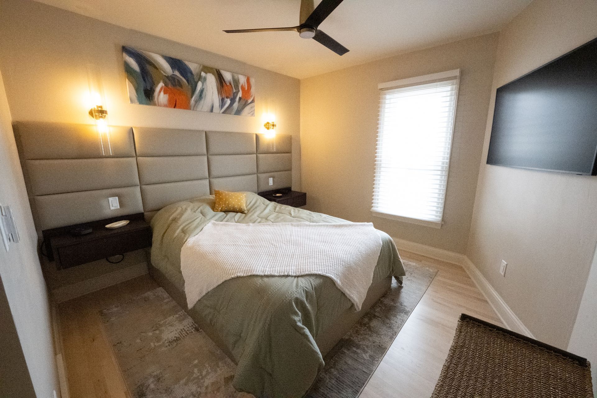 A bedroom with a bed , two nightstands and a painting on the wall.