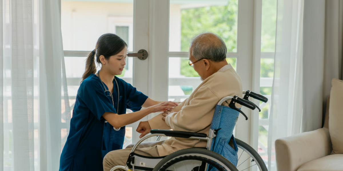 A healthcare worker assisting a person in a wheelchair indoors.