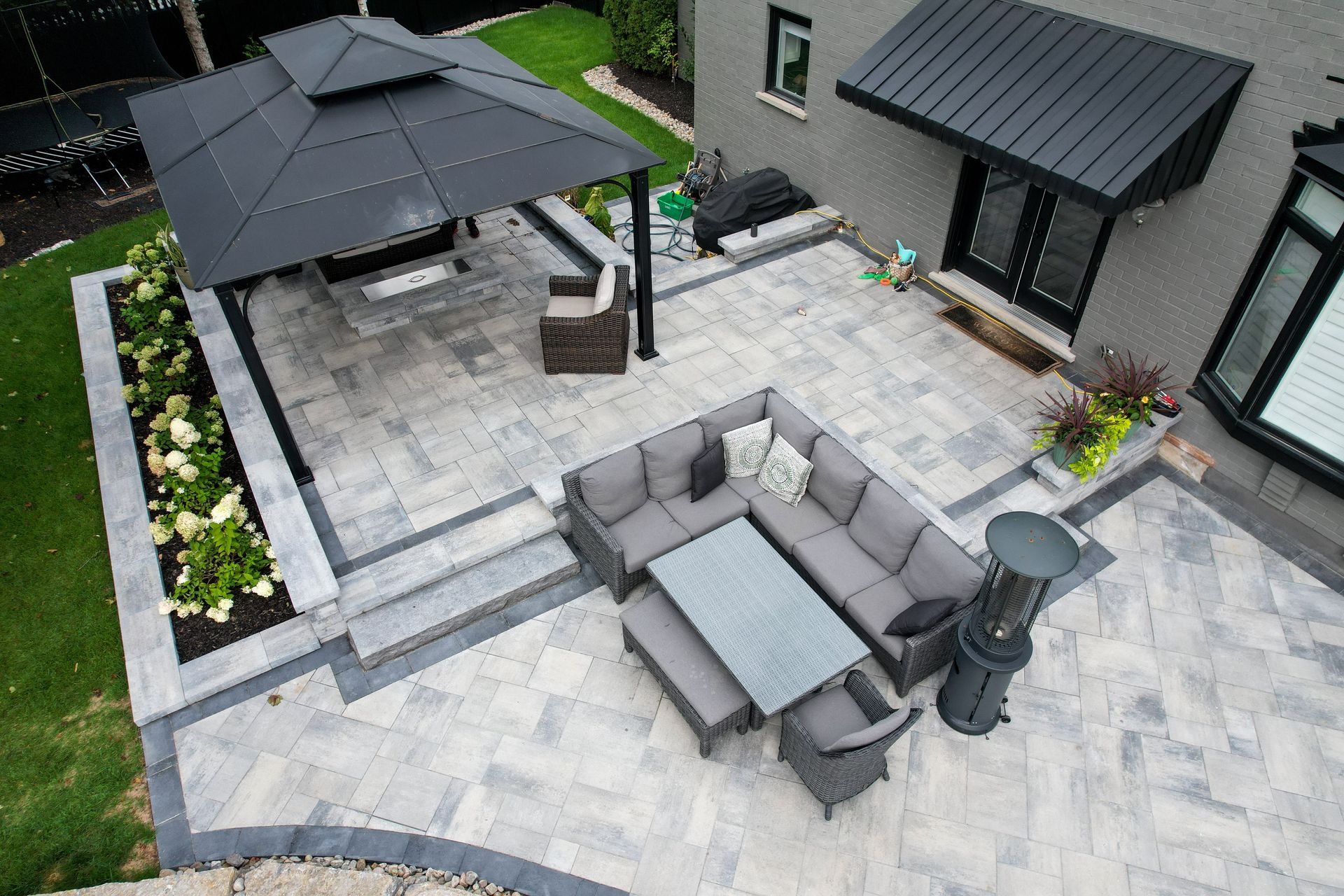 An aerial view of a patio with a couch , table , chairs and umbrella.